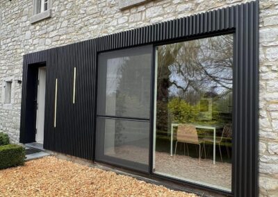 Bardage extérieur noir sur façade en pierre